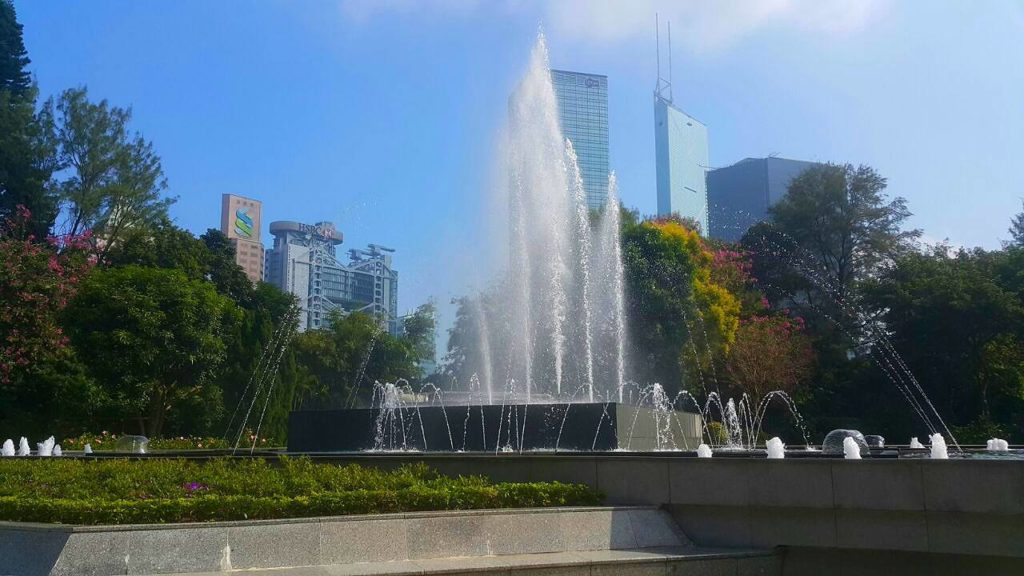 Hong Kong zoological and botanical garden, fountain and buildings on a bright day